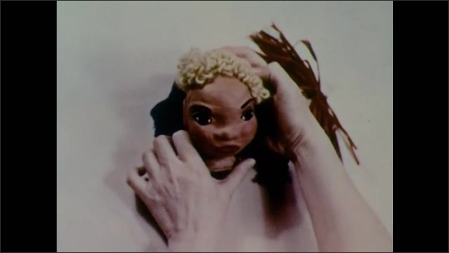 1950s: Hands paint puppet head. Hands place hair on puppet head ...