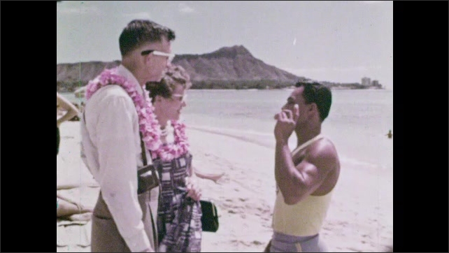 1960s: Two tourists in leis approach a man. Man gestures. Male tourist questions. Man points towards Diamond Head. Female tourist questions.