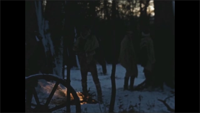 1770s: Four men stand in snowy woods around a fire. Horses and carriage wheels nearby. 