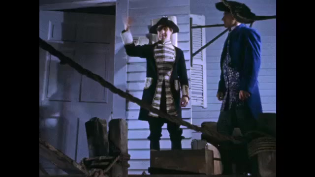 1700s: Colonial men talk and carry goods on dock. Man attempts to purchase barrel from merchant on dock.