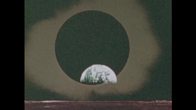 1970s: View of solar eclipse. View of universe. Man speaks. Aerial view of observatory.
