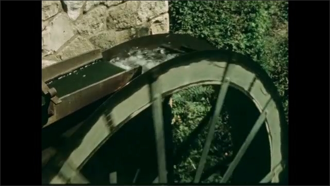 1800s: Man walks up to spinning school door, walks inside. Spinning water wheel. Film slate.