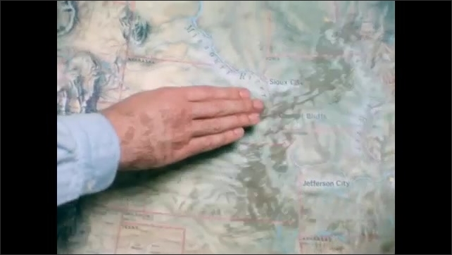 1800s: Film slate. Person traces finger along river on map of United States, leading all the way to Pacific Ocean from the Midwest.