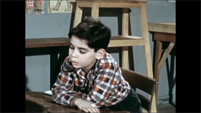 1950s: Clapboard. Girl standing outside, waves and exits. Clapboard. Boy at desk, looks at booklet. 