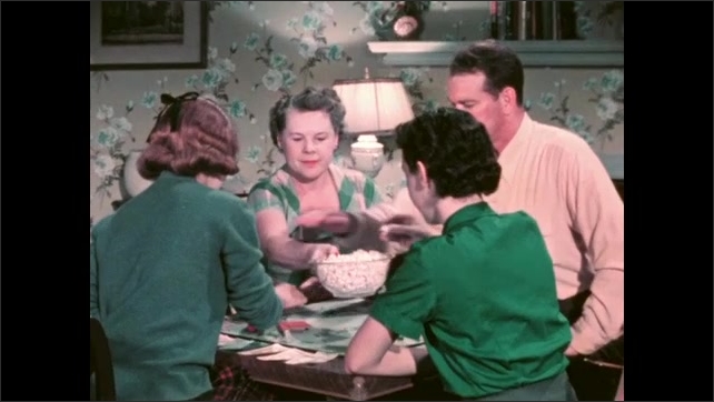 1950s: Family sits and plays a board game and passes popcorn. Girl in a soda fountain chatting and visiting. 