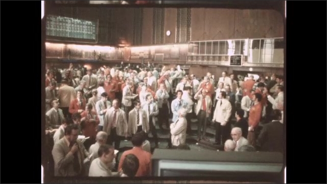 1970s: Traveling on train tracks by oil refinery. Group of people on floor of stock exchange.
