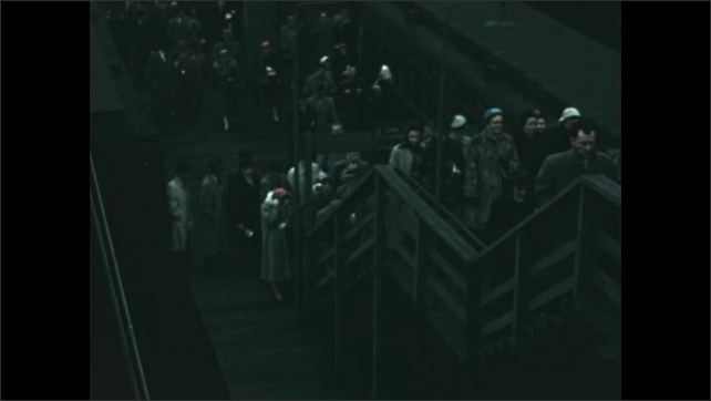 Decade: train arrives at railway station in Chicago. Passengers leave platform. Crowd takes stairs to street in city.
