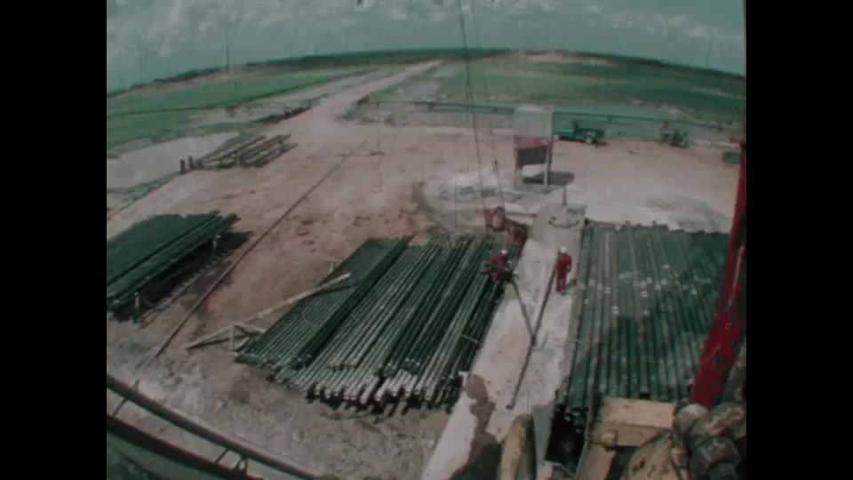 1970s: Pipe being lifted by the crane. Oil workers struggling with the ...