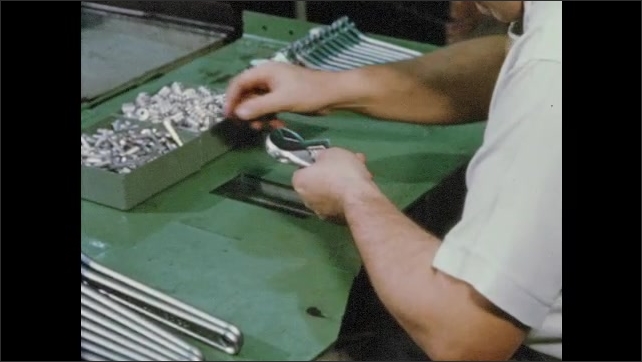 1950s: Worker assembles adjustable wrench parts at workstation. Hands use adjustable wrenches to tighten nuts on machinery.