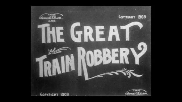 1900s: Caption reads "THE GREAT TRAIN ROBBERY."  Robbers with guns break into train station.  Men hide.  Man leans through window.  Men hit station agent and knock him down.