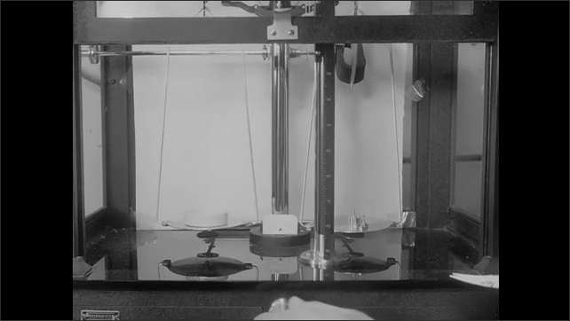 1940s: Man in lab places liquid from dropper onto tray, places tray on scale in device. Scale inside device. Tray on scale. Three men take radiation measurements and photograph material in box.