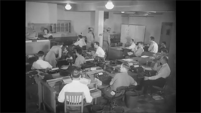 1940s: Buildings, homes, warehouse, businesses. Sprinklers water crops in town. People at desks with typewriters in office, faced towards man behind counter at front of room.