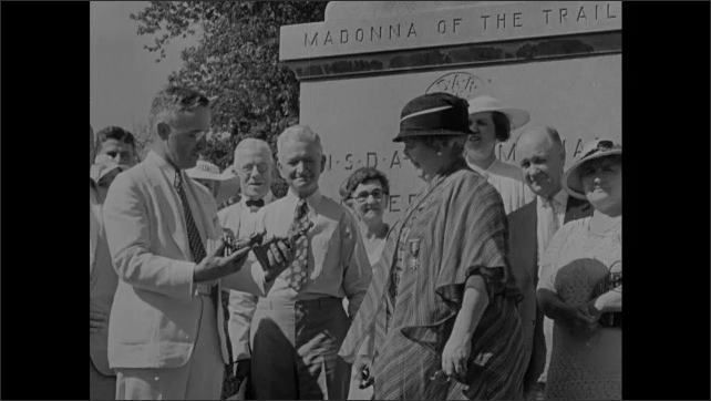 1940s: Soldiers run in No Man's Land as bombs explode. Soldiers march with American flag. Harry S. Truman with  Madonna of the Road statue for dedication, holding two statues. Officer shakes hands.