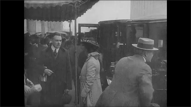 1910s: People and vehicles on street. Title card. Man and woman get out of car. Man pays driver.