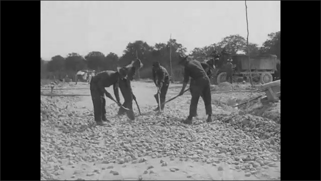 1920s: Laborers shovel rock.