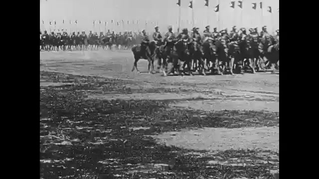 1910s: Military parade.  Men on horseback.  Cars.  Soldiers walk.  
