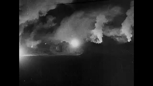 1910s: Night.  Tank fires on battlefield.  Soldiers sit in snow.  Men dance.  Man grabs dog.  Men march down hill.  