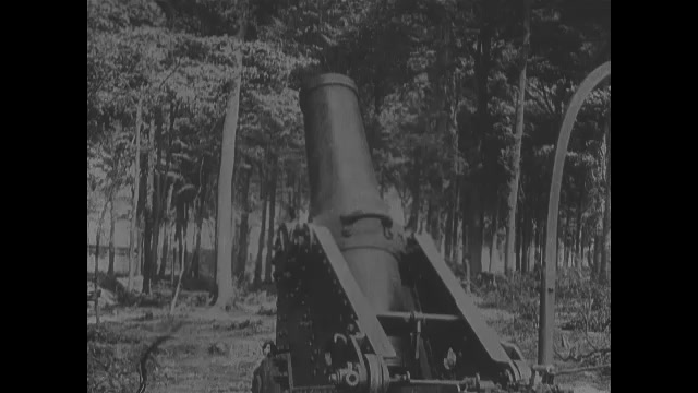 1910s: Mortar cannon fires into air. Intertitle cards. Trucks drive down road, people on sides of road watch. Trucks drive down road pulling carts of supplies, weapons.