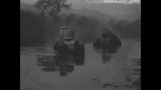 1910s: Two tanks drive across shallow water and up slope on shore.