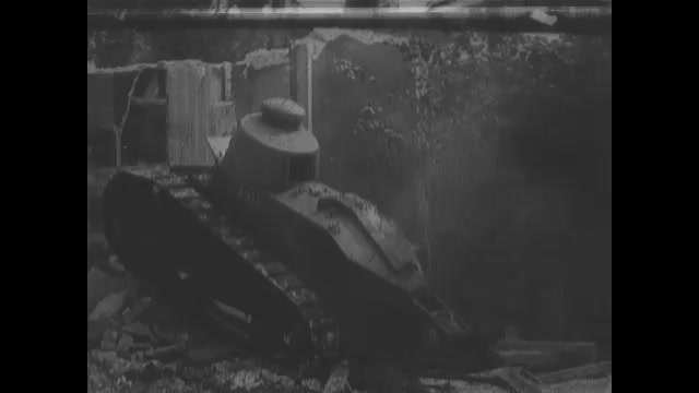 1910s: Tank drives over rubble from destroyed building in city. Tank drives up to brick wall.
