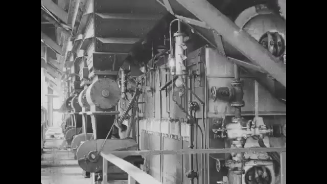 1910s: Machines inside factory. Intertitle. Man push cart full of coal in mining tunnel to elevator. Elevator lifts cart full of coal and dumps it up top.