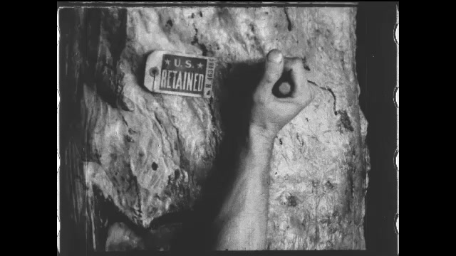 1910s: Hand stamps a side of meat. Intertitle. Men use hacksaws to cut through hanging sides of beef. Man uses cleaver to finish separating the side into two pieces. Intertitle.