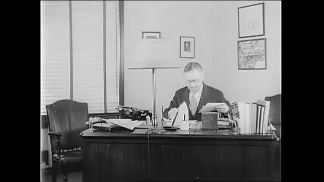 1940s: Man at desk, man enters, man gives man paper, man exits. Men talking at desk, look at paper. 