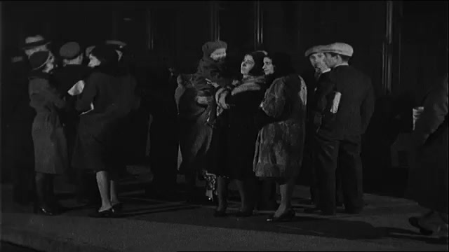 1930s: People wait on a train platform. Men in suits walk beside a train. Men surround a hidden Al Capone. Men board rail cars. Man holds a coat over his face as he he walks through a darkened car.