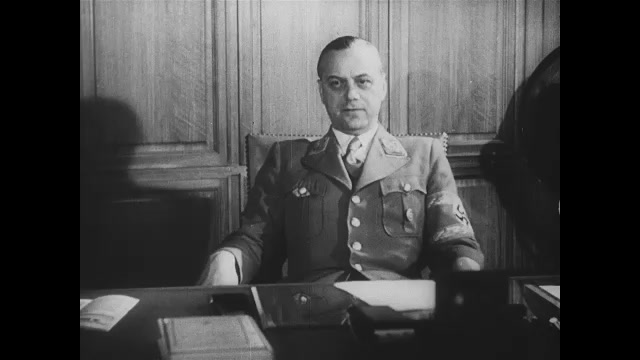 1930s Germany: Nazi officer sits at desk in office and speaks.