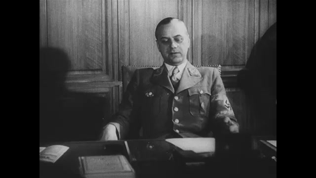 1930s Germany: Nazi officer sits at desk in office and speaks.