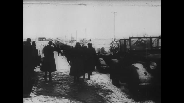 1930s Germany: Men wheel bicycles down road in snow. Vehicles and people in snowstorm. Nazi rally.