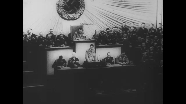 1930s Germany: Hitler speaks and gestures. Men cheer and clap.