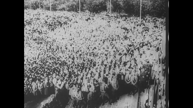 1930s Germany: Adolph Hitler points and speaks to large youth group in Thuringia. Huge crowd of young men salute and shout during speech. 
