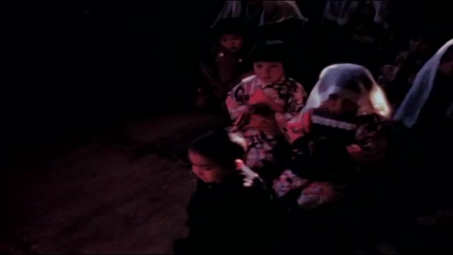 1940s: Women and small children in kimonos and veils kneel and sing from books in church.
