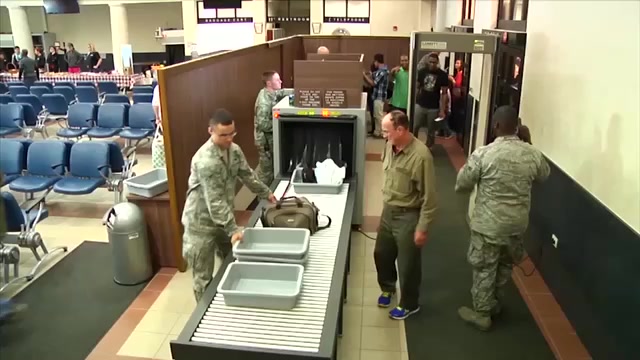 2010s: Airport security checkpoint - soldiers in camouflage fatigues man the conveyor belt and metal detector. Man takes laptop out of backpack. Female soldier smiles. Soldier in news studio speaks.