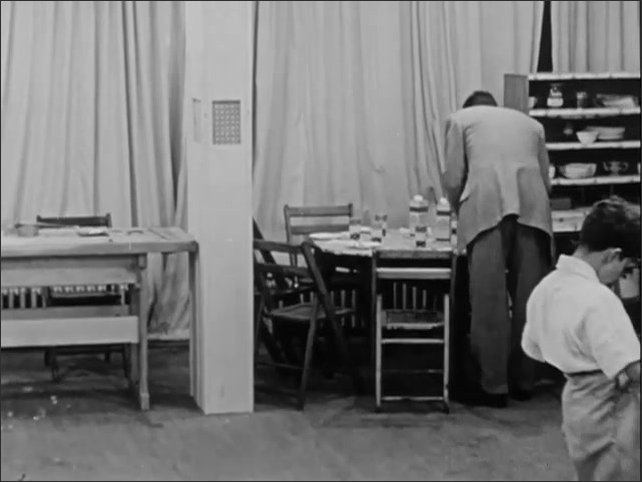 1950s: Boys tucking shirts in. Man clearing dishes from table. Boys exiting room.