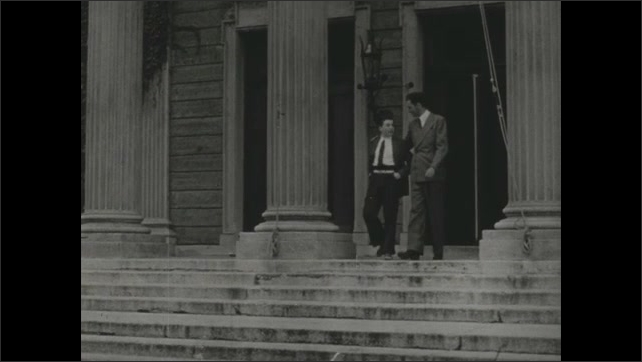 1940s: Man talking to boy at desk, man and boy shake hands. Tilt down exterior of building, man and boy exit. Boy walks from building, waves to man. End title. 
