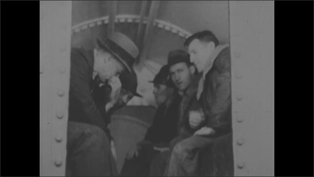 1930s: Men climb into chamber. Gauge moving. Low angle, man turns knob. Men sitting in chamber. Gauge moving. Men in chamber. Shots of men working in tunnel.  