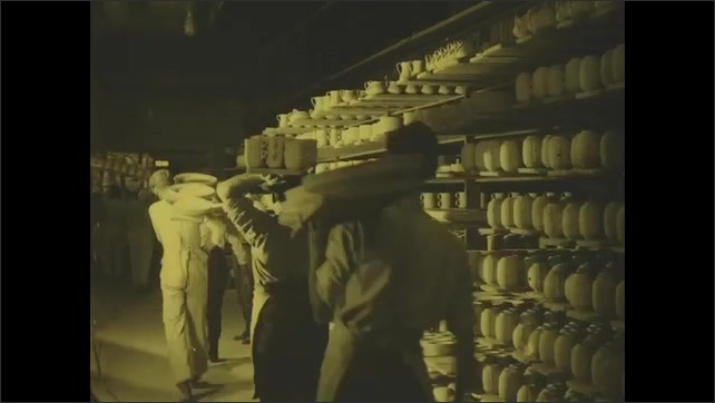 1910s: Title card. Men carrying large planks full of pottery. Men moving pottery from shelf to kiln, some balanced on their heads.