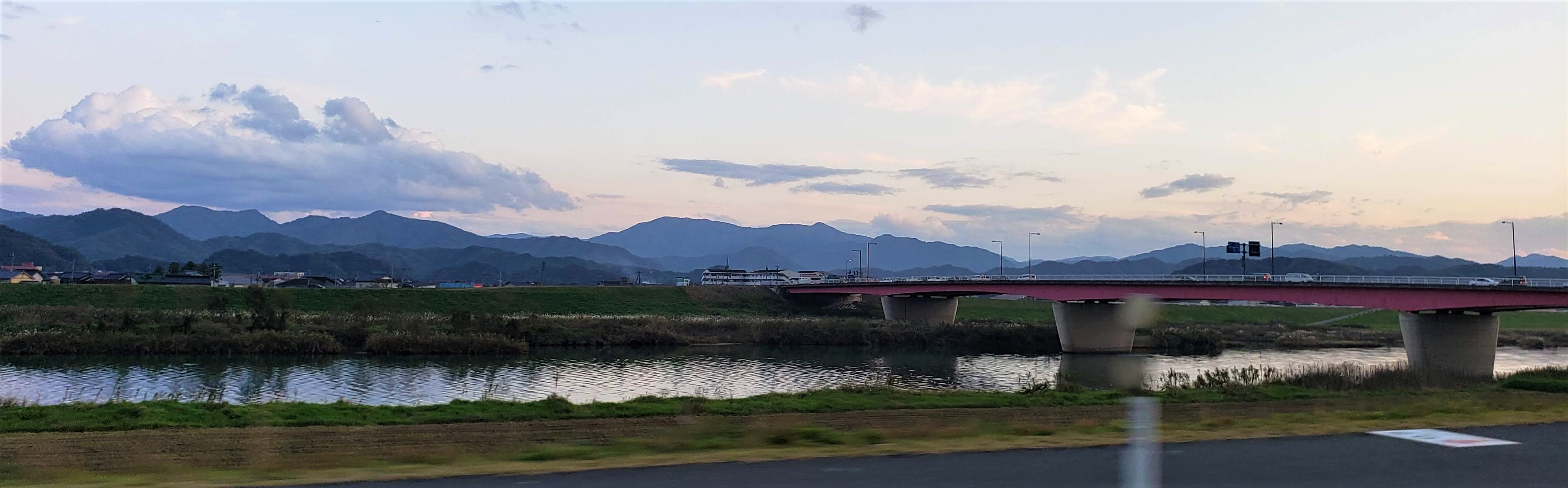 a river and bridge with mountains in the distance