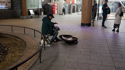 A musician next to the fountain and statue of Gyōki. 