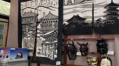 Masks and a tapestry on a shop wall.