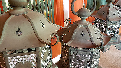 Metal lanterns hanging along a walkway in a shrine.