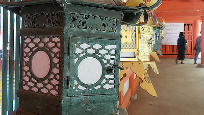 Metal lanterns line a walkway in a shrine.