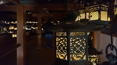 Metal lanterns hanging in a walkway underneath part of a shrine.