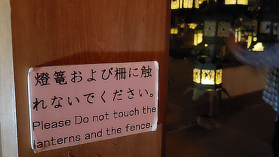 A sign asking for visitors to not touch the lanterns and fence.