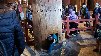 A person crawling through a hole in one of the temple's support columns. This is apparently done for good luck.