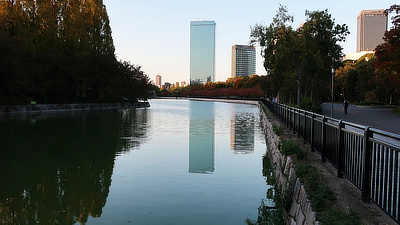 A lake surrounding the Castle and a skyscraper on the other side of the park.