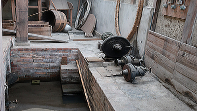 A lined trench behind a vat.