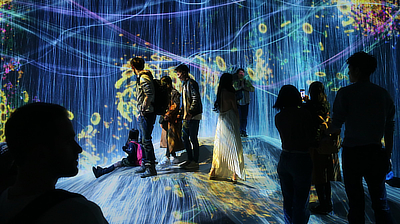 People interact with the "Universe of Water Particles on a Rock where People Gather" exhibit.